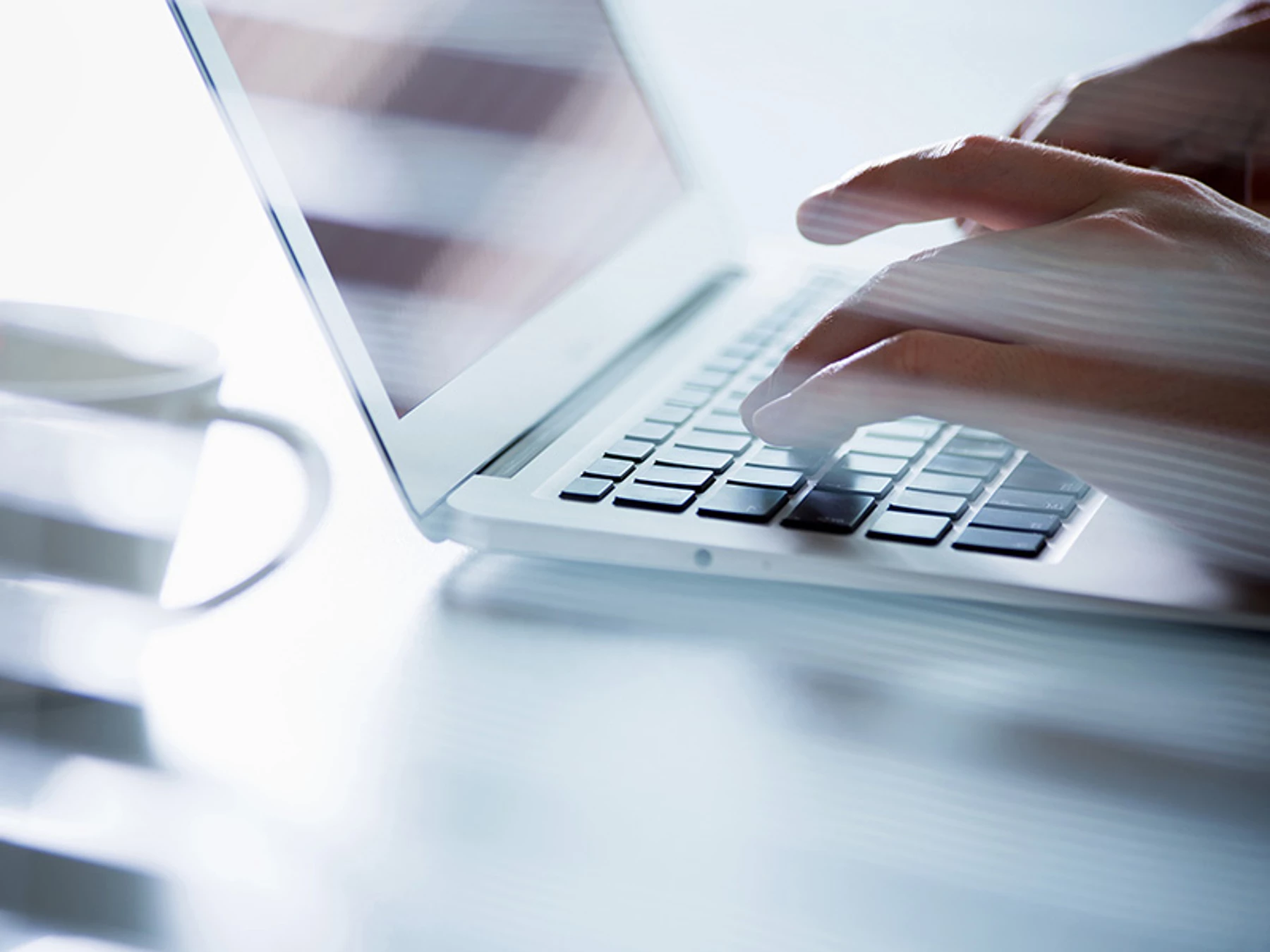 Nahaufnahme von Händen, die an einem Laptop tippen